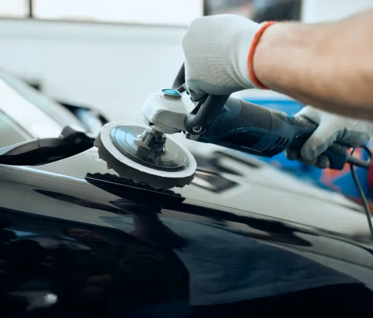 A person polishing the exterior of a car, enhancing its shine and appearance