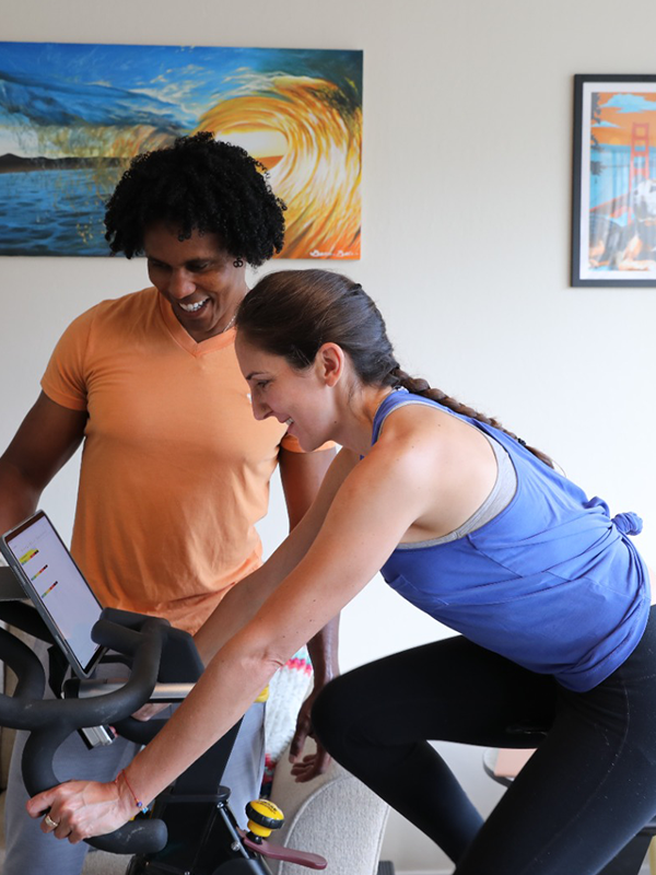 Coach Junior helping a woman improve her running form during indoor cardio training.