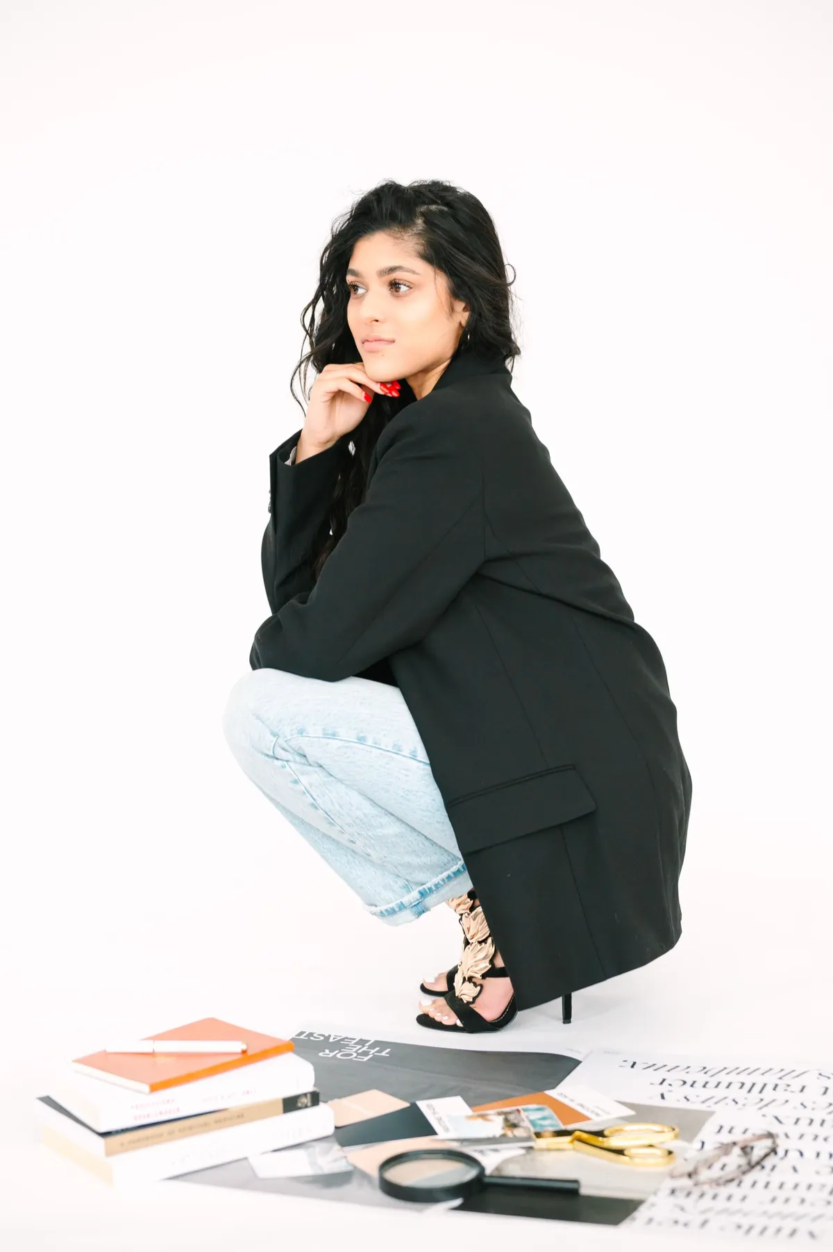 Amber Farooqui in a black blazer with books and creative materials