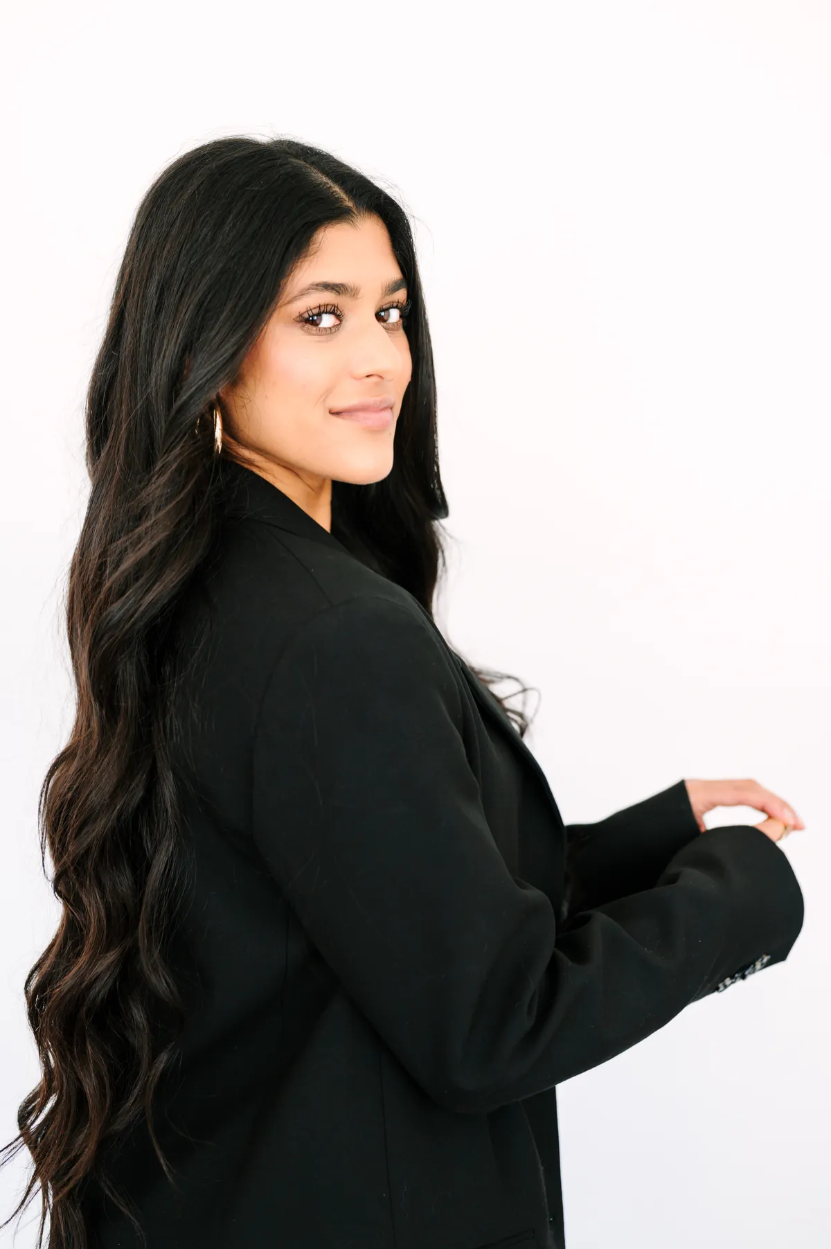 Amber Farooqui looking over her shoulder in a black blazer