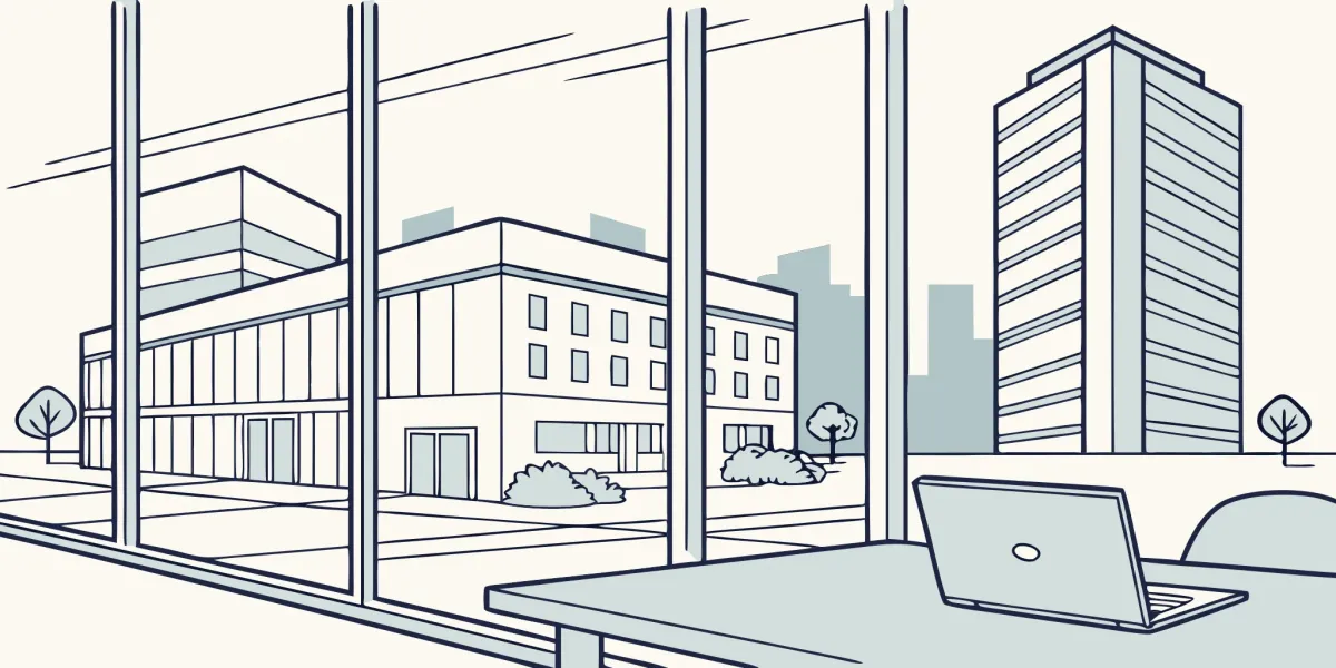 A laptop on a desk for commercial property management, with a view of modern office buildings.