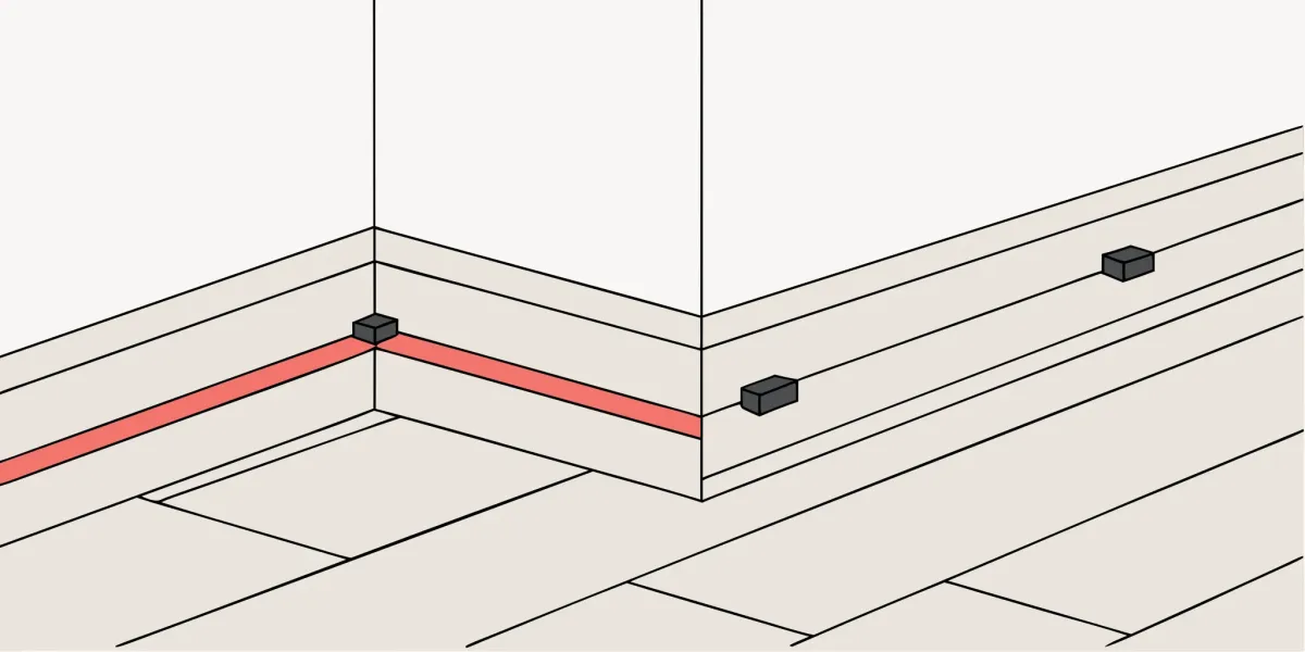 A red chalk line on a subfloor to create a straight guide for starting hardwood flooring.