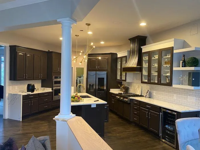 a kitchen with dark cabinets and white columns