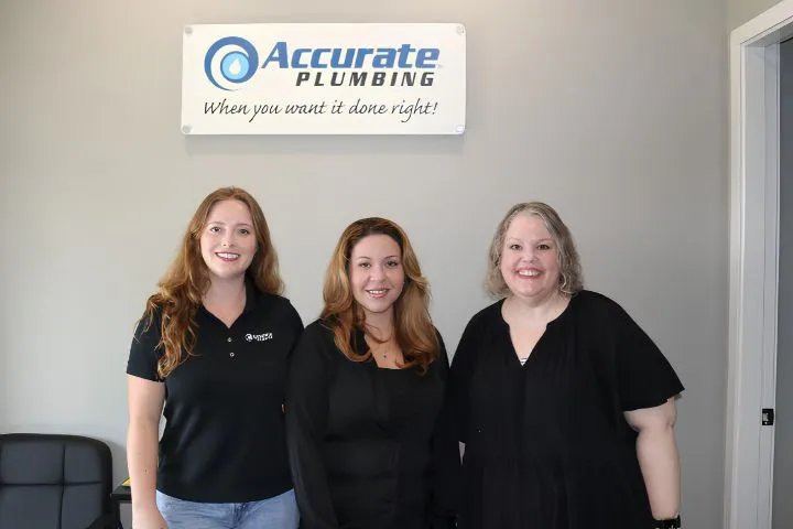 Three staff members in black uniforms standing together beneath the company sign, ready to coordinate your plumbing inspection.