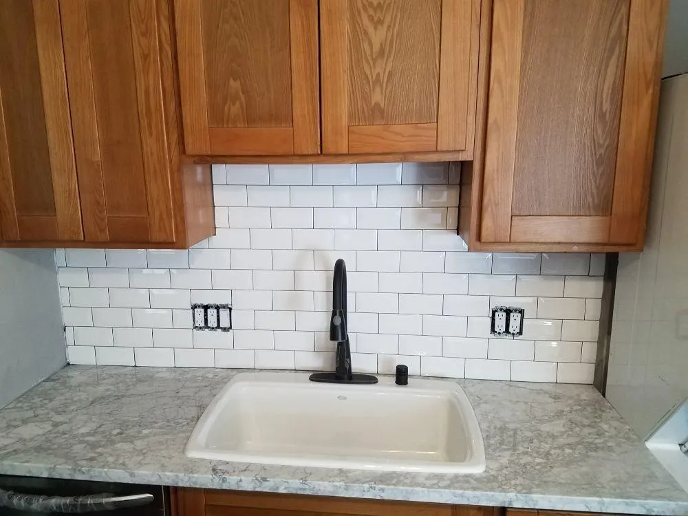 Kitchen sink installation with new faucet and tiled backsplash