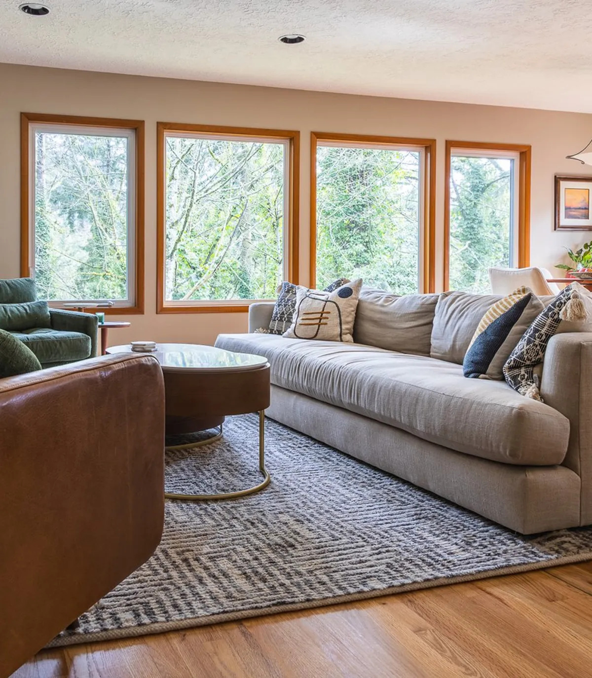 Bright living room with large windows, neutral sofa, and textured area rug.