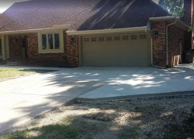 Concrete driveway replacement at residential brick home by Quick Concrete Solutions Central Iowa