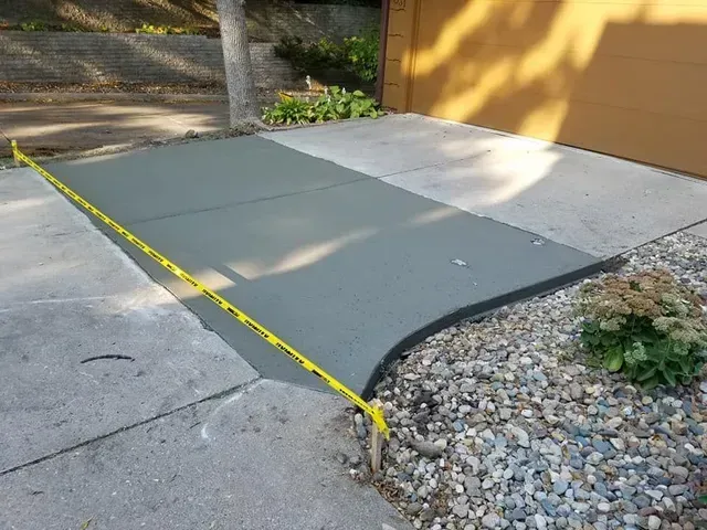 Concrete driveway apron repair curing next to garage by Quick Concrete Solutions Central Iowa