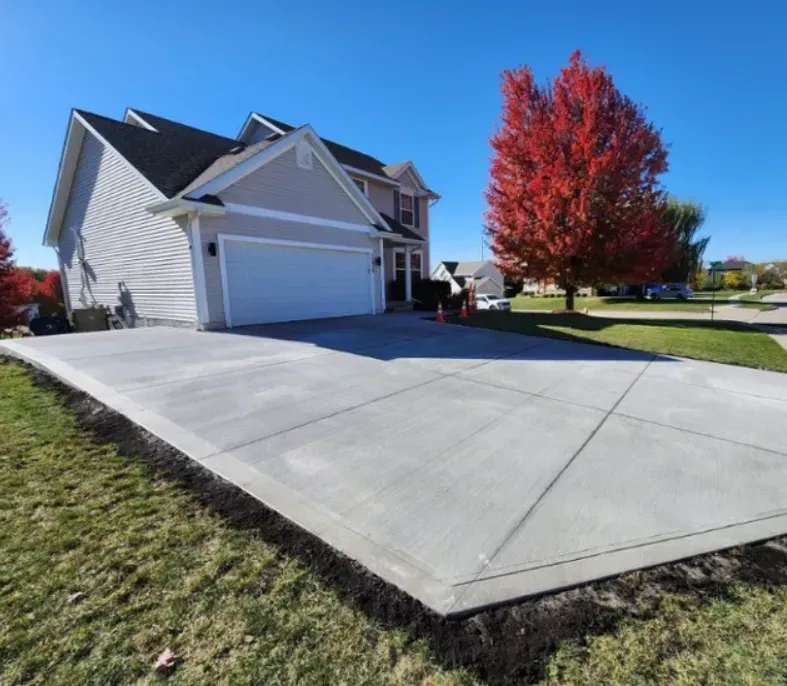 New residential concrete driveway installation with fall landscaping by Quick Concrete Solutions Iowa