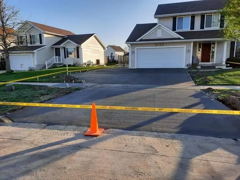 Freshly poured residential concrete driveway curing at dusk by Quick Concrete Solutions Central Iowa