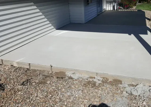 New concrete patio slab installation beside residential garage by Quick Concrete Solutions Iowa