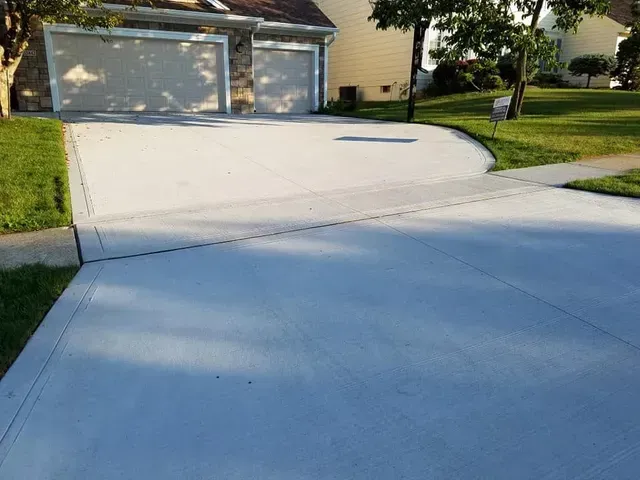Wide residential concrete driveway with curved street apron by Quick Concrete Solutions Central Iowa
