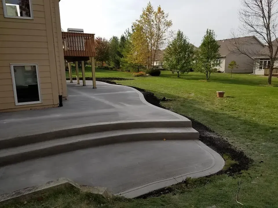 Curved residential concrete patio with tiered steps by Quick Concrete Solutions Central Iowa