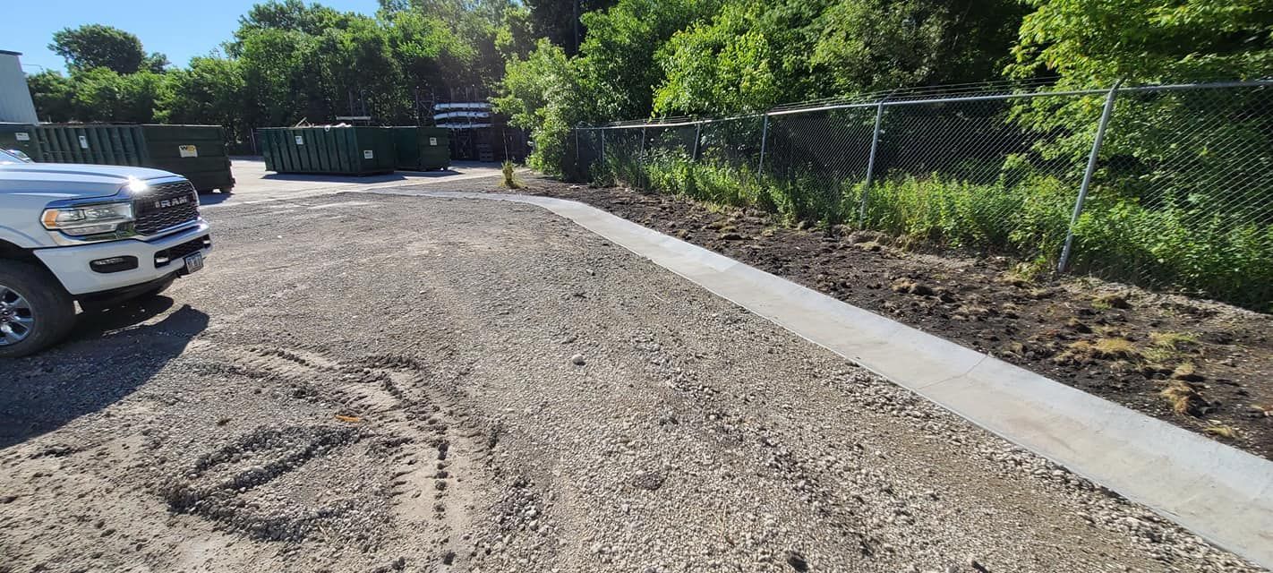 Concrete curb installation at commercial property with chain link fence by Quick Concrete Solutions Iowa