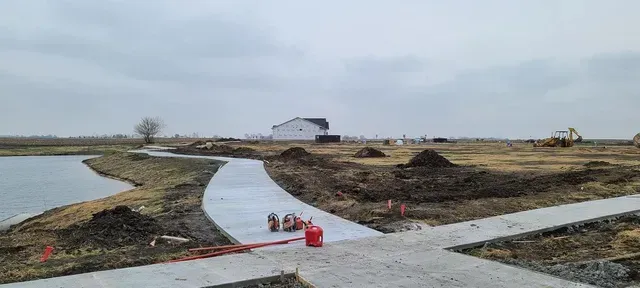 Winding concrete pathway installation through rural development site by Quick Concrete Solutions Iowa
