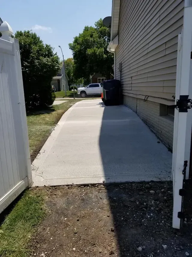 Residential concrete side walkway installation between home and fence by Quick Concrete Solutions Iowa