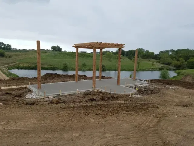 Concrete patio slab with pergola frame at rural pond property by Quick Concrete Solutions Iowa