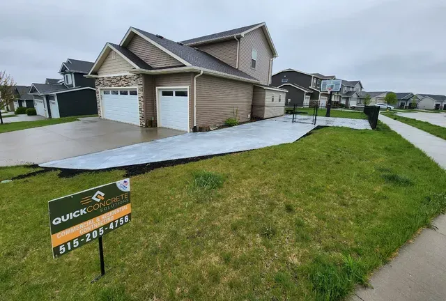 New residential concrete driveway installation with Quick Concrete Solutions yard sign Central Iowa
