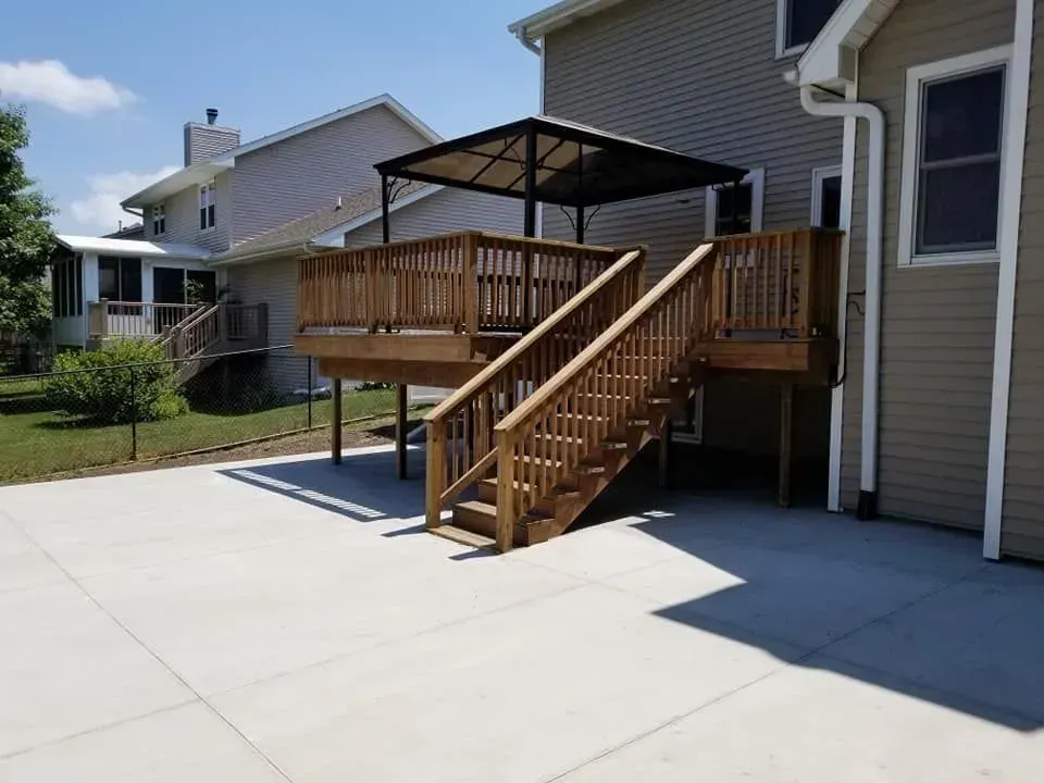 Residential concrete patio installation under elevated wood deck by Quick Concrete Solutions Central Iowa