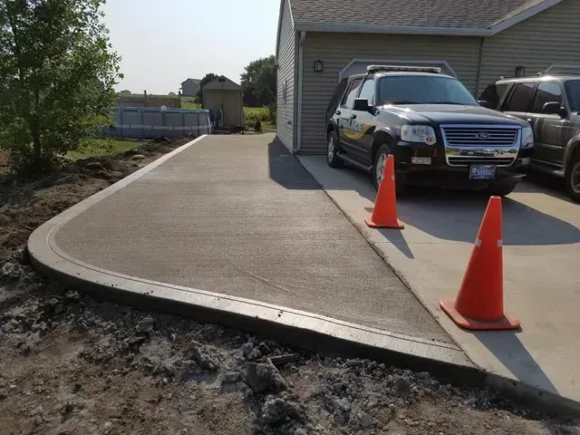 Freshly poured residential concrete driveway extension curing by Quick Concrete Solutions Iowa