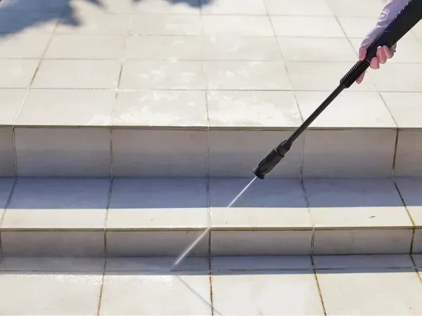 Close-up of pressure washing outdoor tile steps to remove dirt and stains