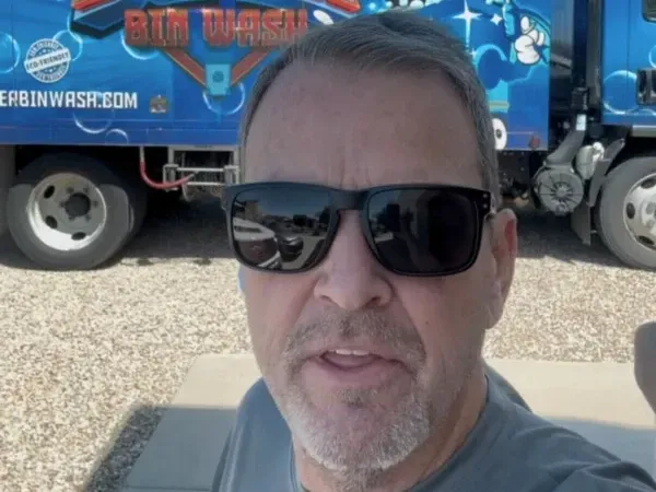 Man standing in front of a professional bin wash truck for residential trash can cleaning service