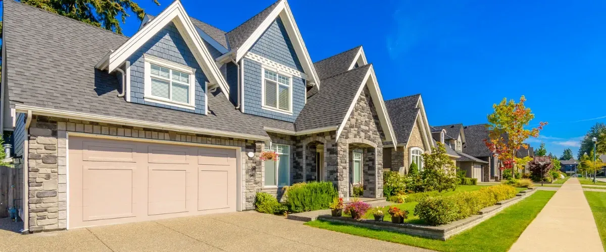 Front view of a clean residential home exterior with fresh landscaping and blue sky.