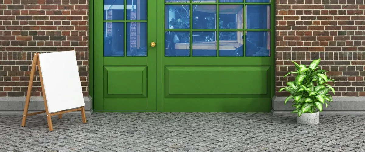 Person wearing gloves cleaning leaves and debris from a clogged roof gutter