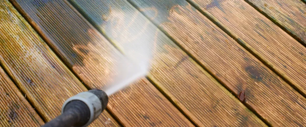 Pressure washer cleaning a wooden deck and removing dirt and grime.