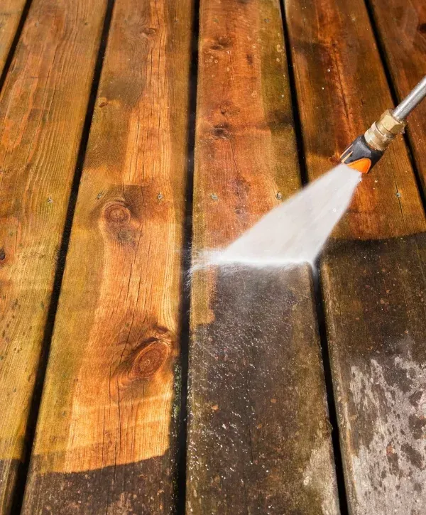 Power washing wooden deck showing clean and dirty sections for comparison.