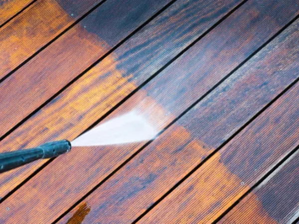 Power washing a wood deck showing clean and dirty sections for comparison.