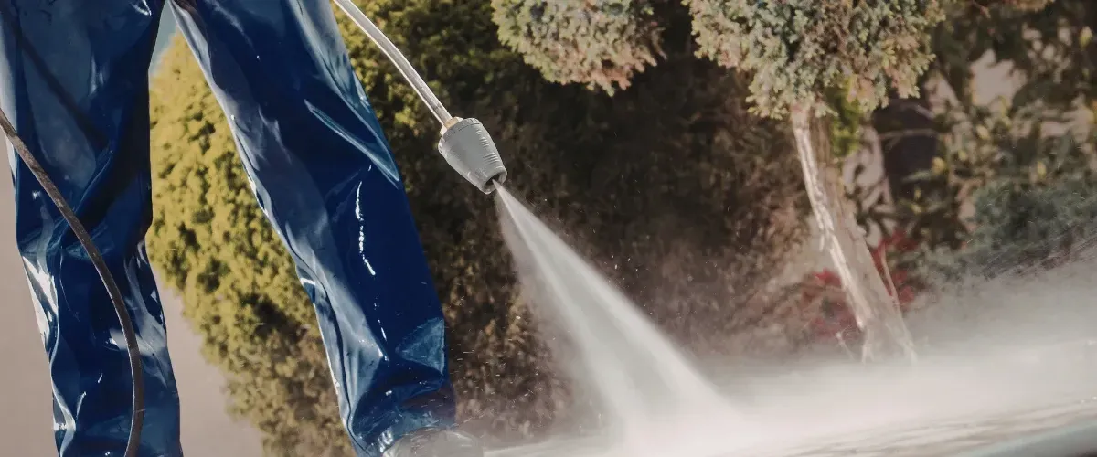 Close-up of a high-pressure water jet cleaning a driveway surface.