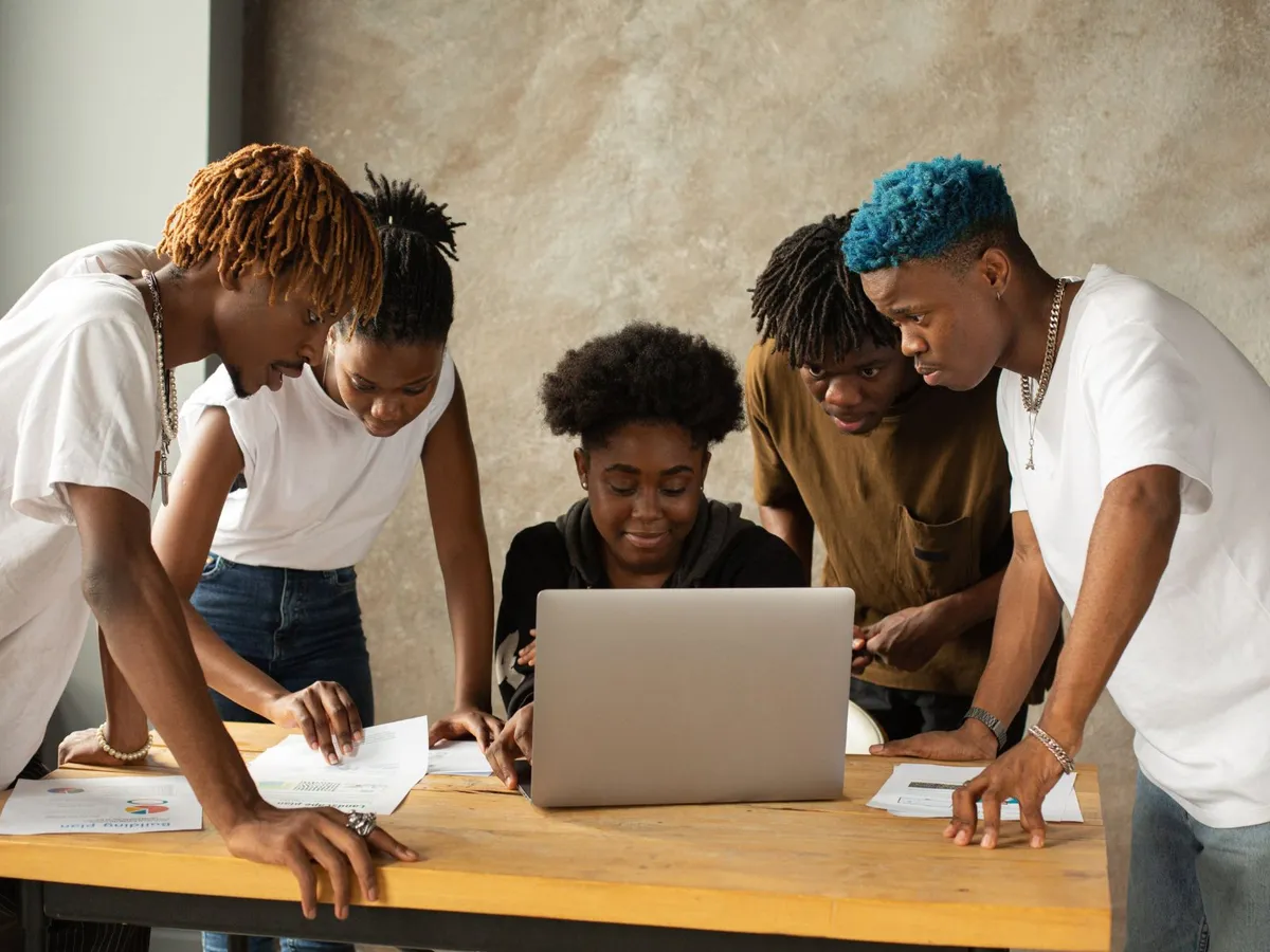 Team of young founders gathered around a laptop planning a startup idea