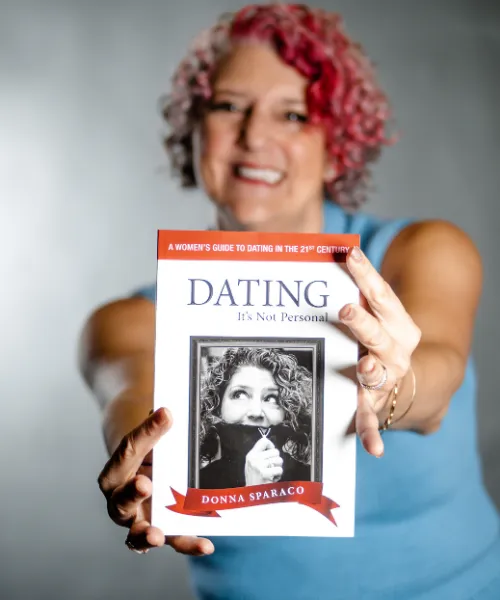 Donna Sparaco Meador holding her book “Dating: It’s Not Personal – A Women’s Guide to Dating in the 21st Century.