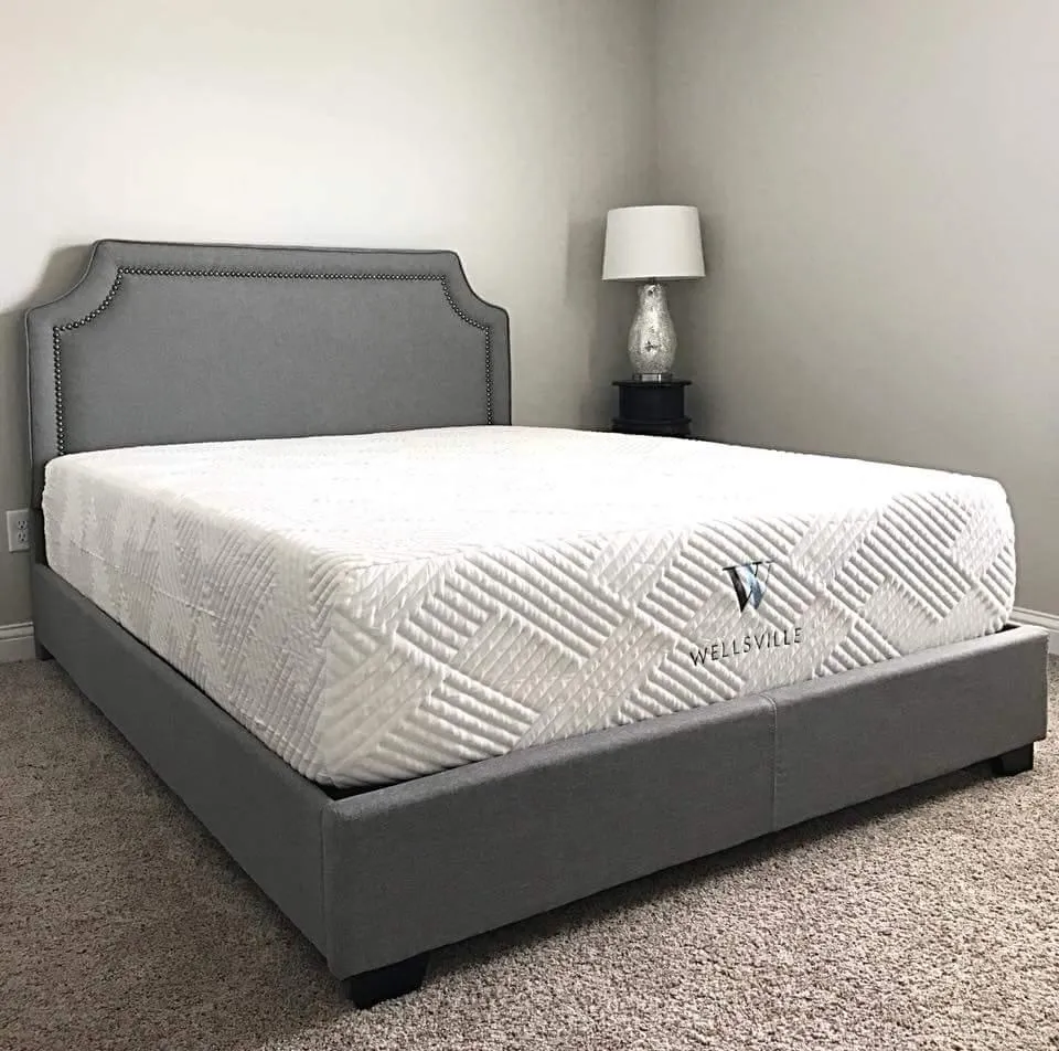 A white gel memory foam mattress from Wellsville on a grey upholstered bed frame and headboard.