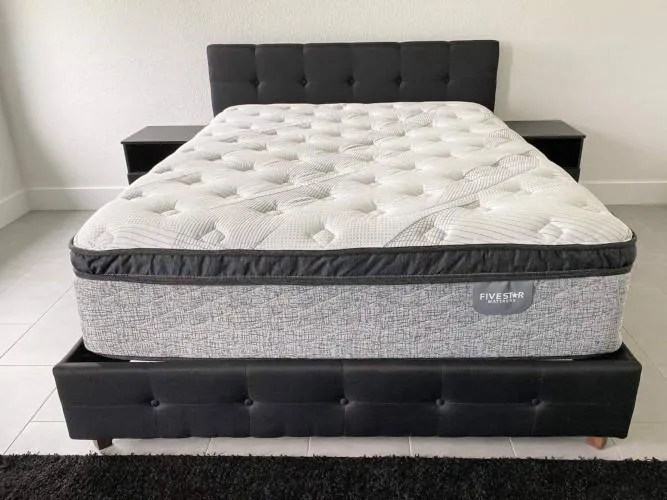 A eurotop mattress with a grey border and white top. The eurotop part is black. Serta.