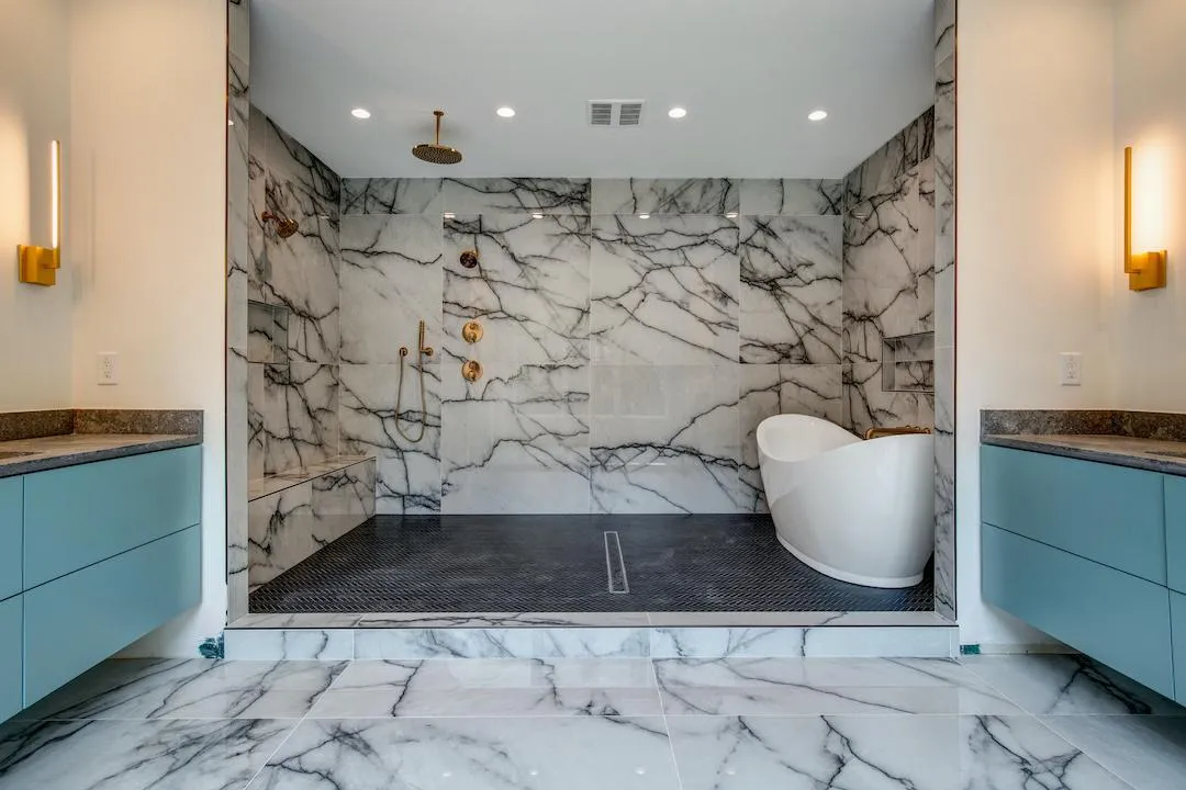Luxury master bathroom with white marble walls, freestanding soaking tub, and dual floating vanities