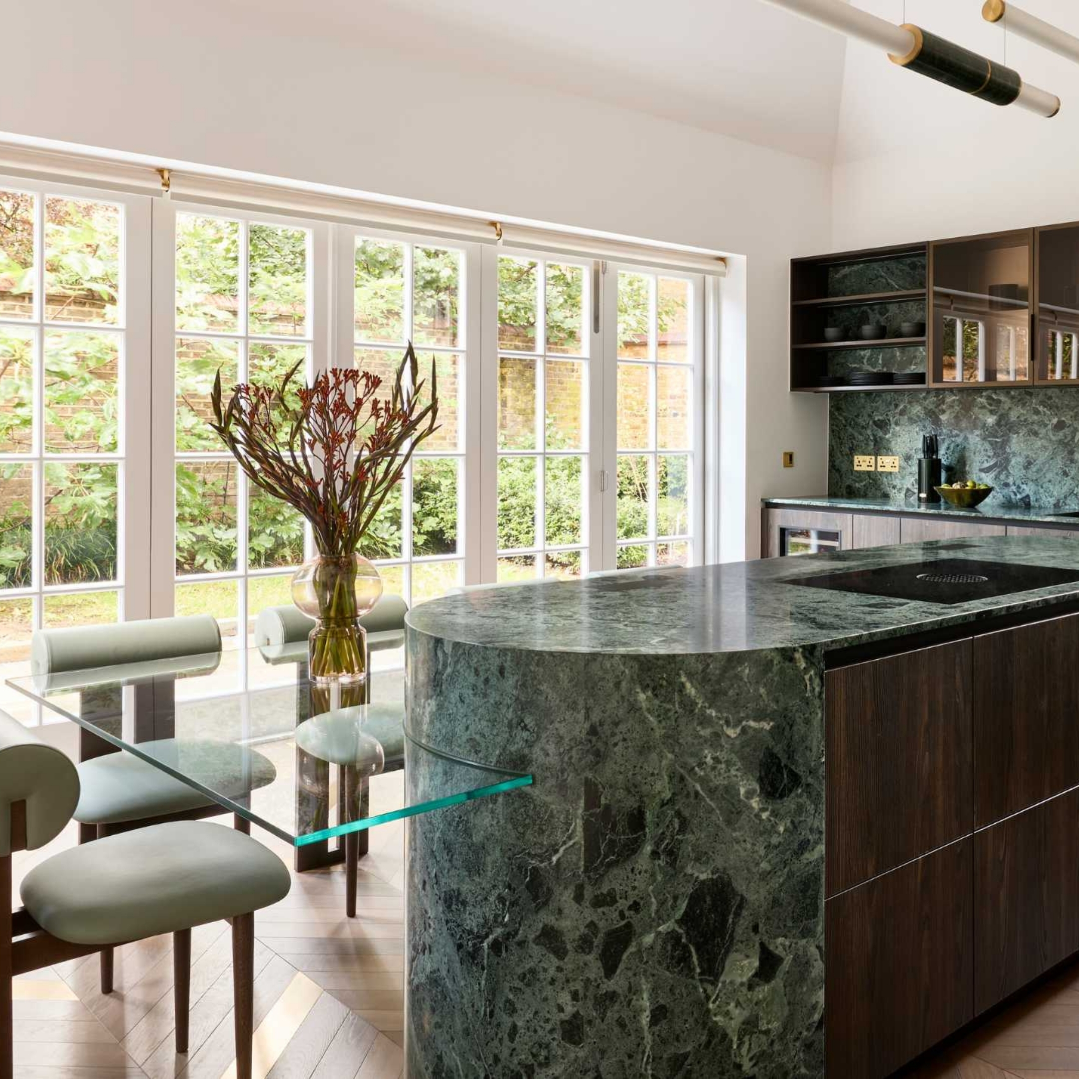 Kitchen with green marble-look worktops and units, glass breakfast bar and stylish art deco chairs. 