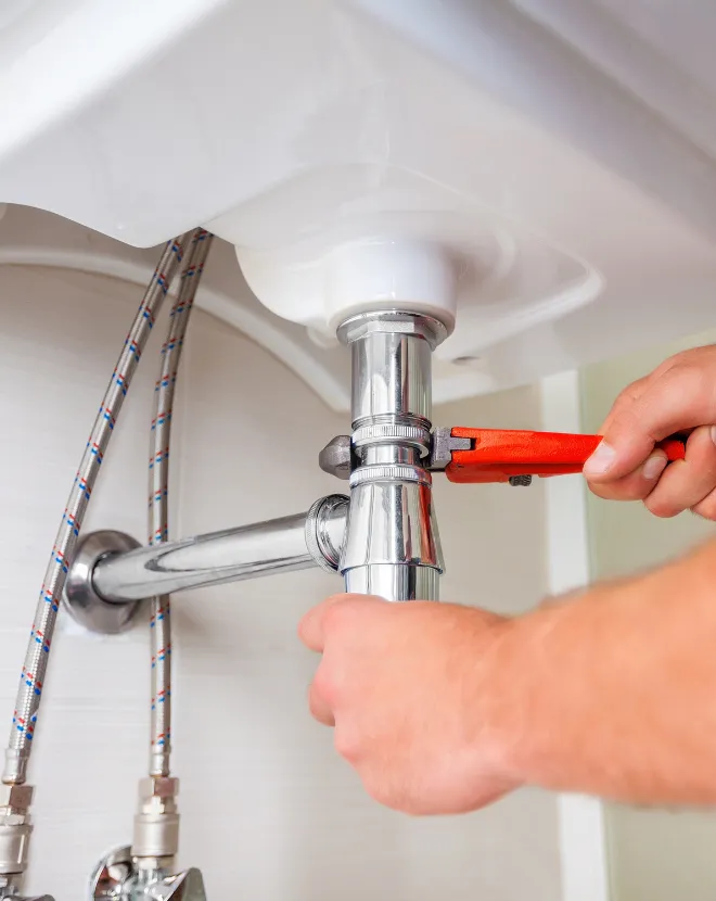 Close up of handyman fixing sink plumbing with wrench providing expert leak repair and maintenance services for homeowners in North Carolina