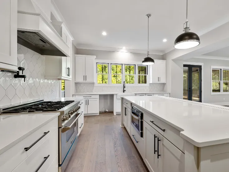 Luxury modern kitchen remodel with white cabinets quartz countertops hardwood flooring and stainless steel appliances installed by skilled remodeling contractors