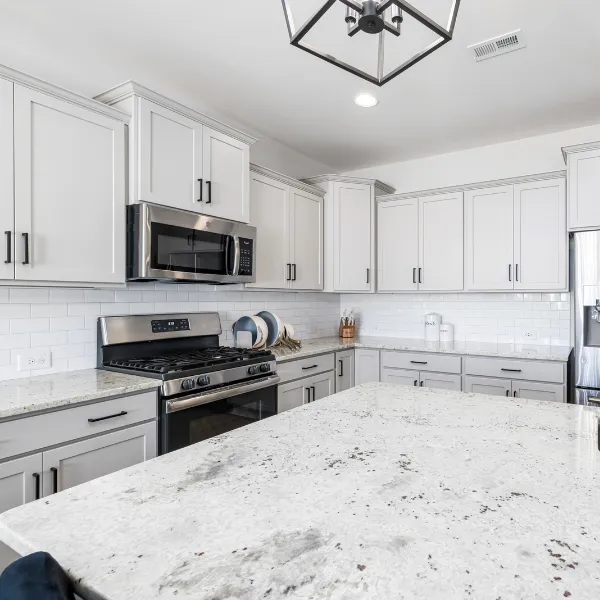 Contemporary kitchen remodel featuring white cabinetry subway tile backsplash granite island and stainless steel appliances for a stylish functional space