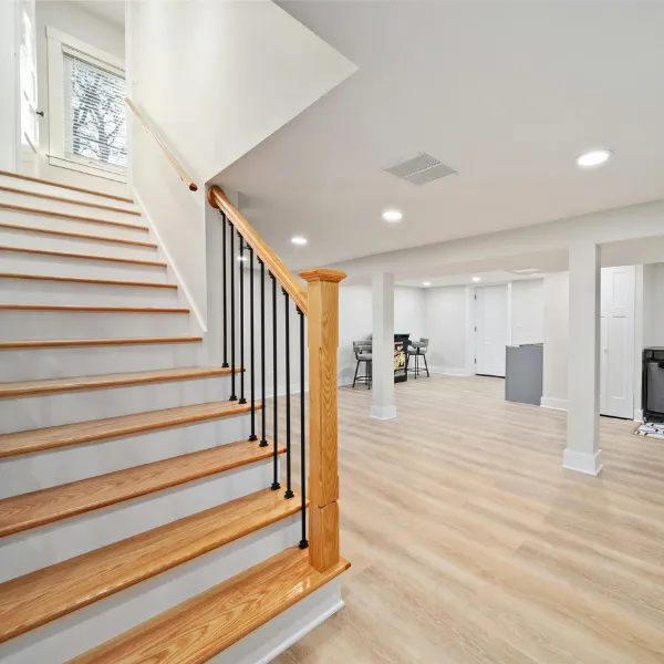 Modern staircase renovation with wooden steps, white risers, and sleek railing design.