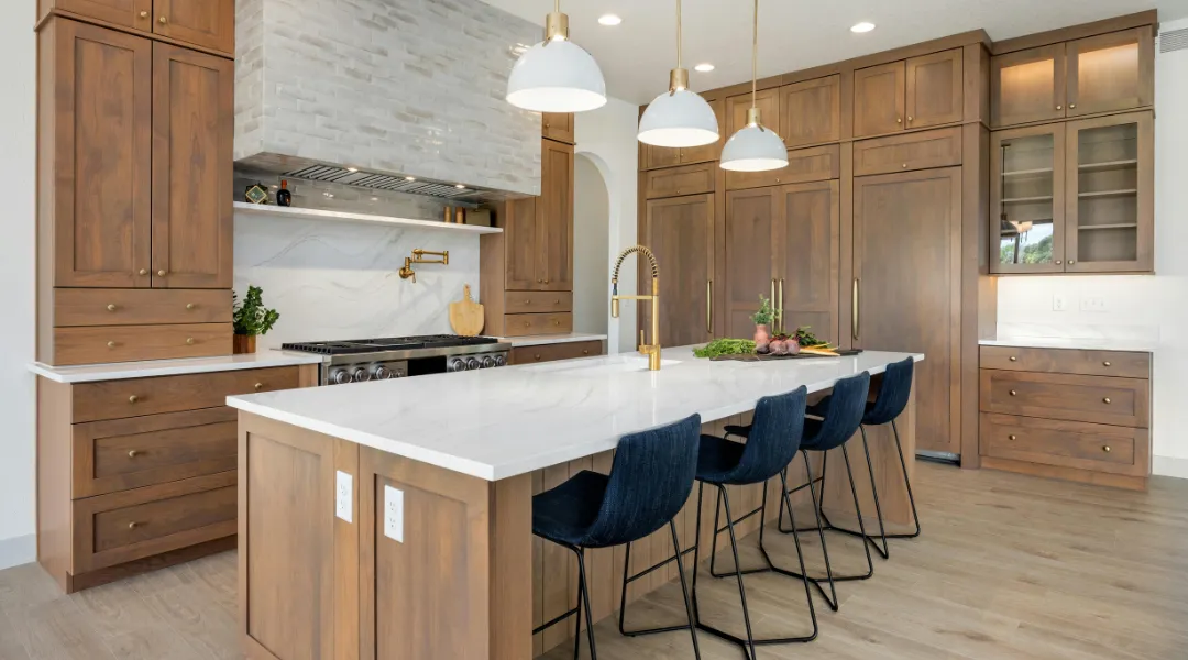Luxury kitchen remodel with custom wood cabinetry, white quartz countertops, large center island, modern pendant lighting, and stainless steel appliances.