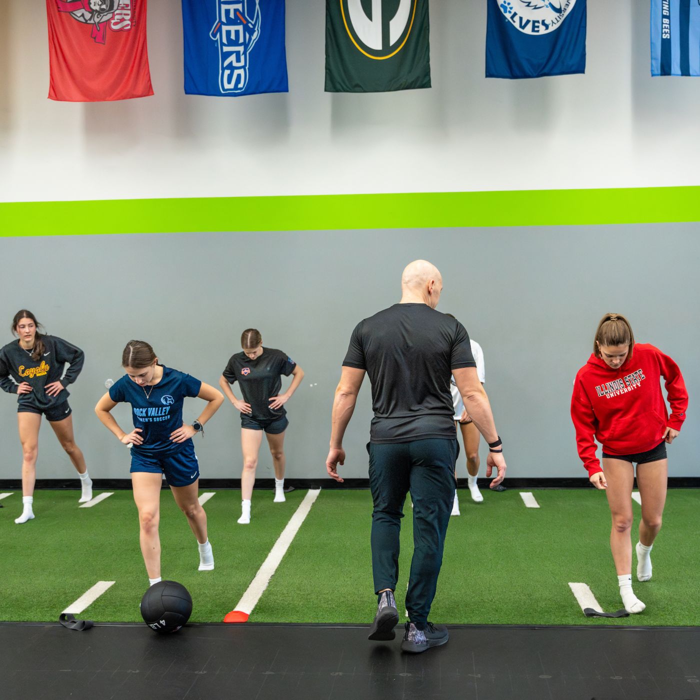 Coach Justin leading a group of female athletes through a warm up on turf
