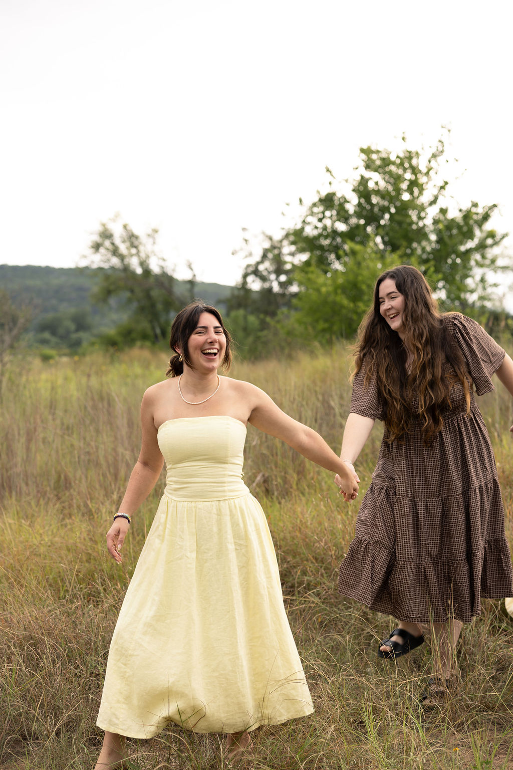 Two female participants of Level Up Club laughing and holding hands outside 