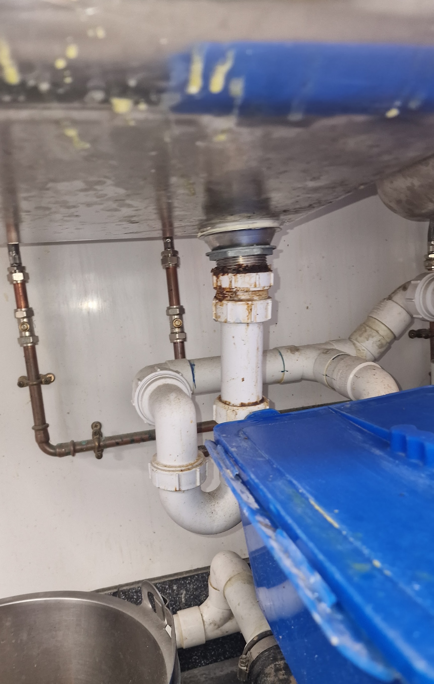 Plumber repairing a leaking kitchen sink waste trap and copper supply pipework in Plymouth