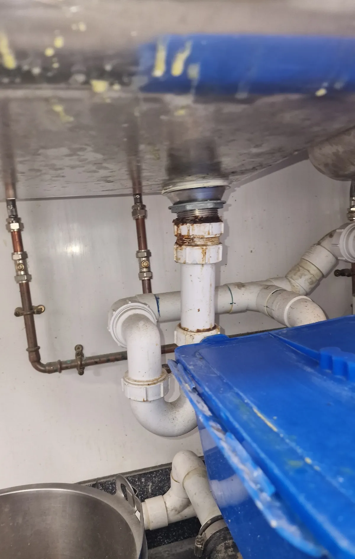 Plumber repairing a leaking kitchen sink waste trap and copper supply pipework in Plymouth