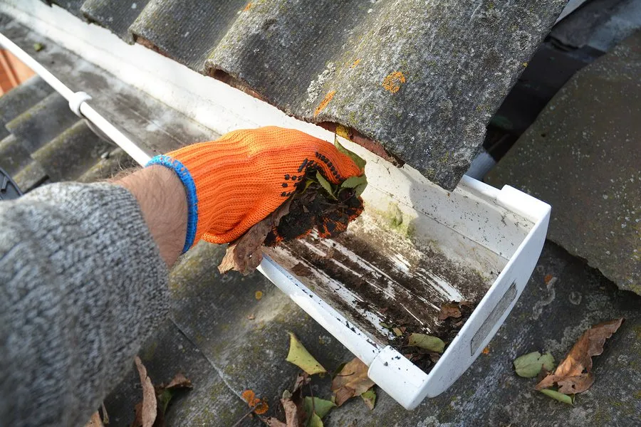 Team member hand cleaning dirt from gutter system