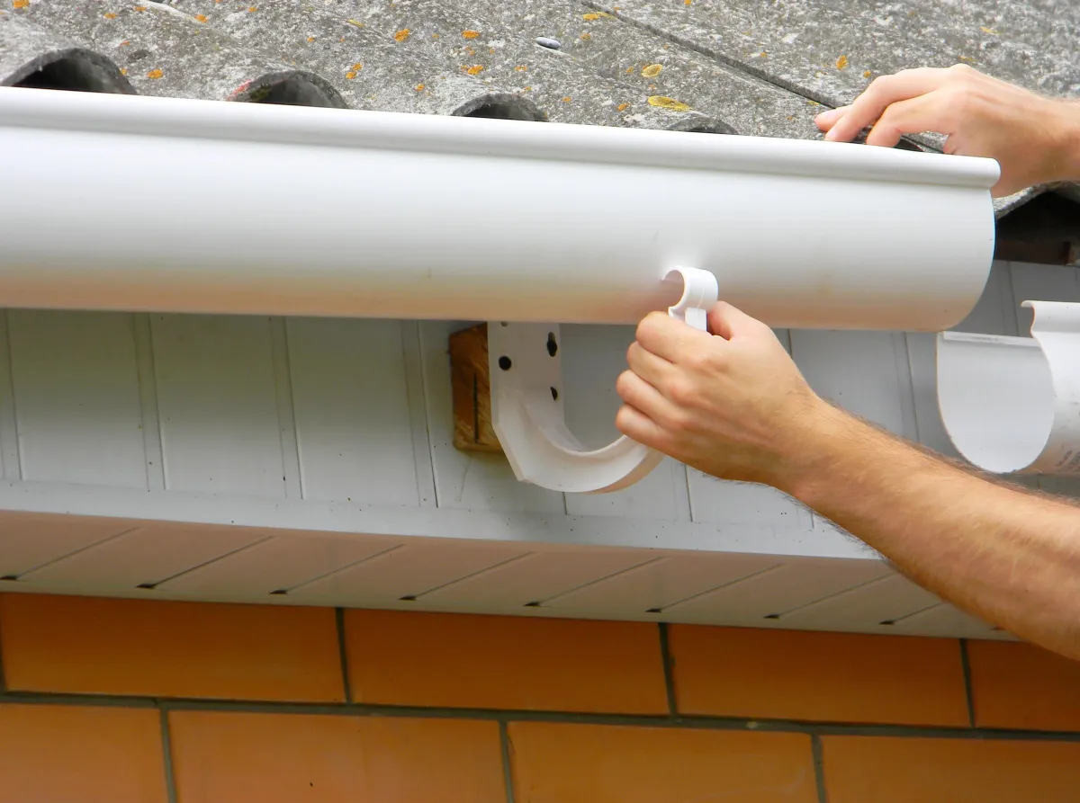 Team member installing plastic roof gutter on a residential house in Albany Ga. 