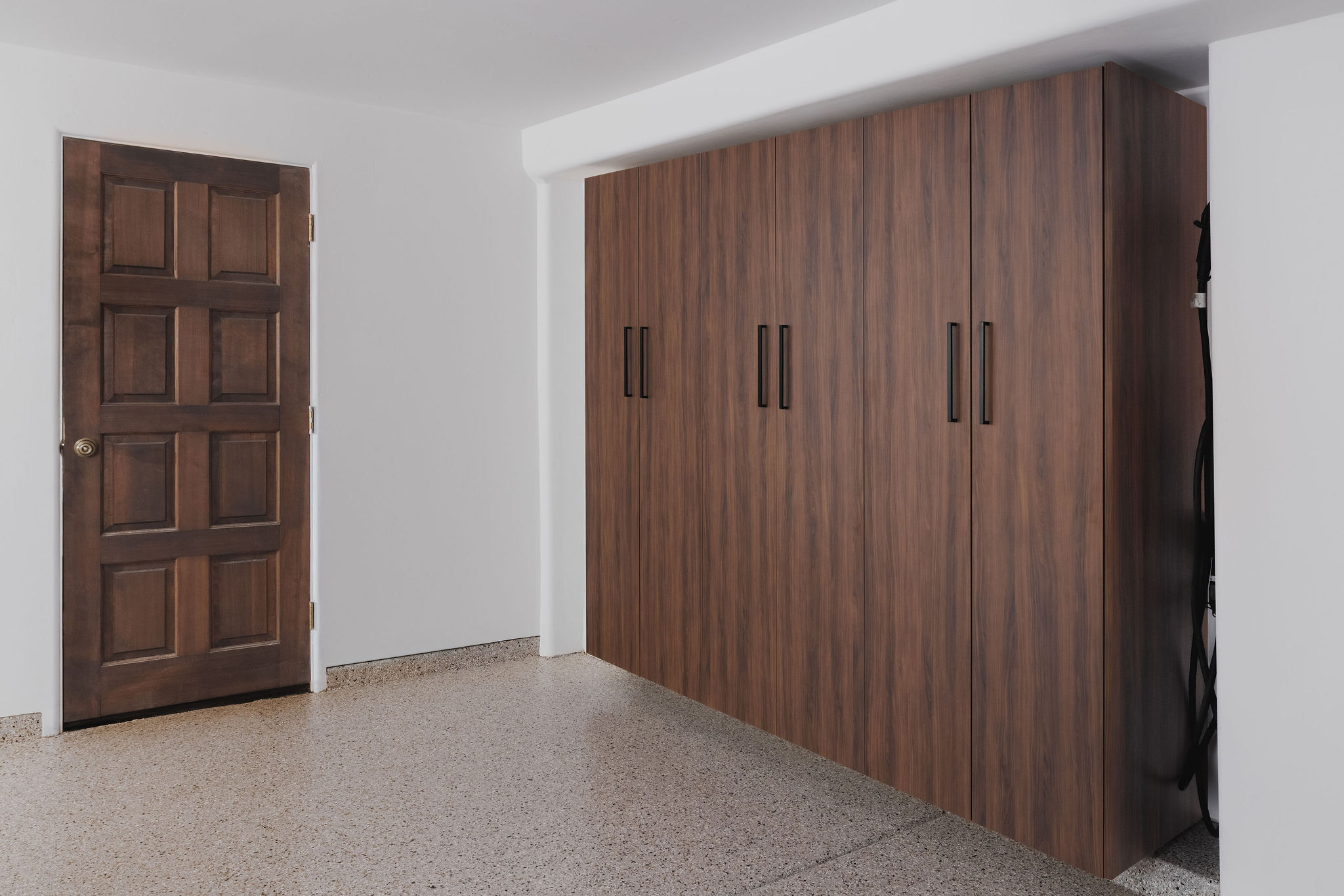 Streamlined wood finish custom garage cabinets spanning a home storage area